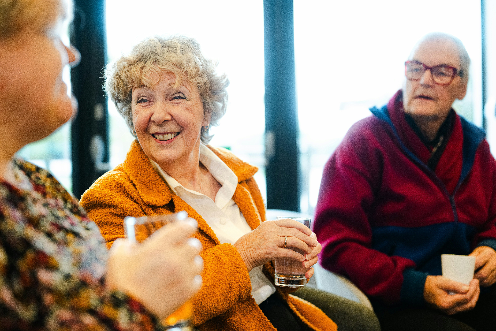 Senior friends laughing together over drinks at a community gathering